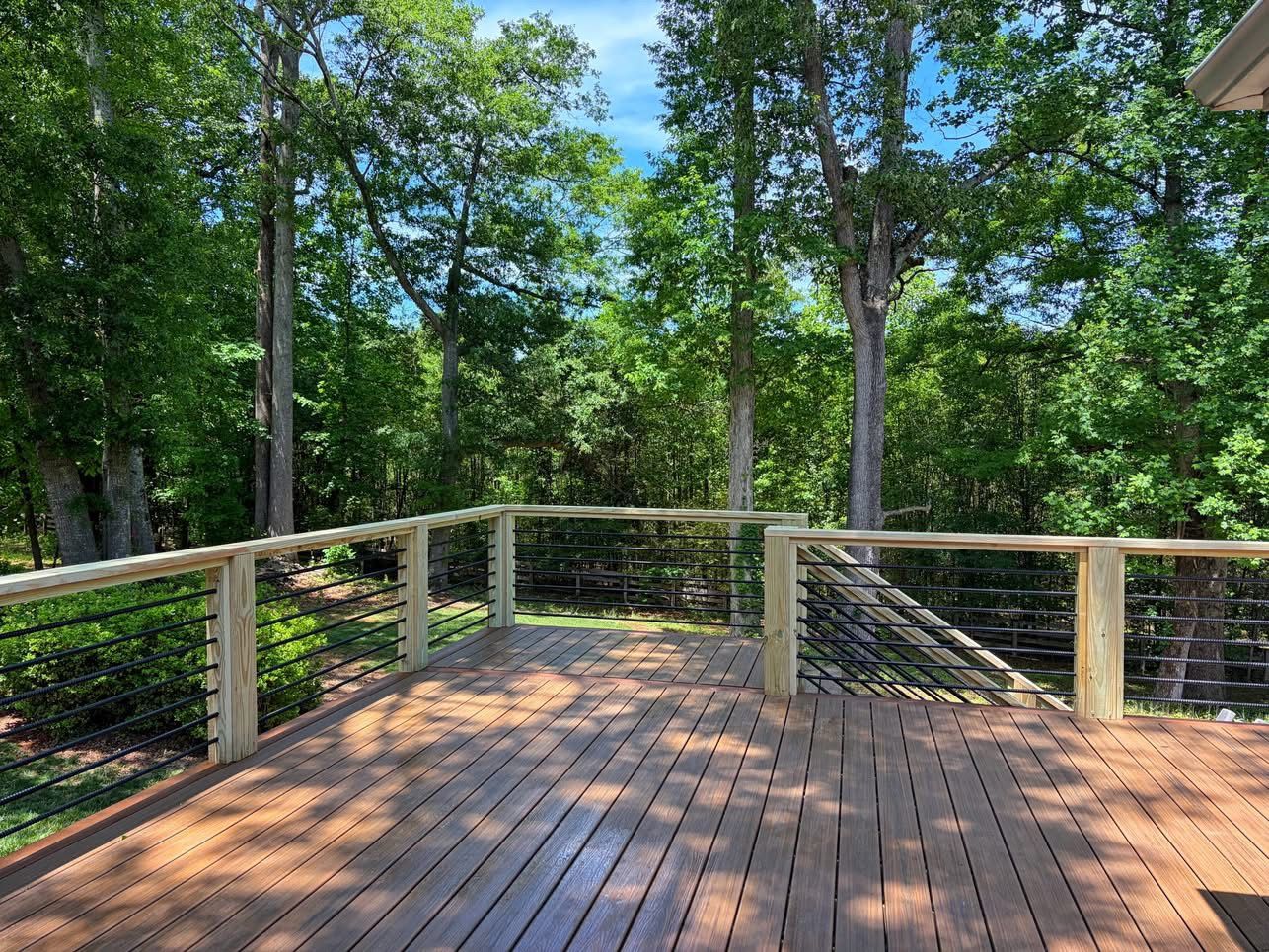 Composite deck with cable railing in a private wooded backyard